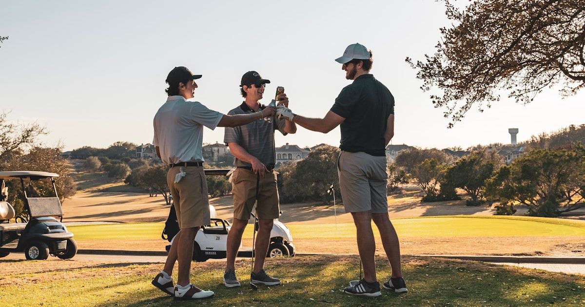 Two golfers chatting on a sun-lit golf course during a round