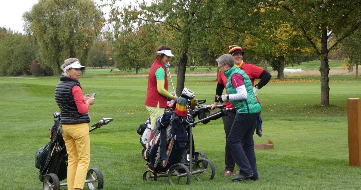 Four women golfers gathered together on the course with golf bags